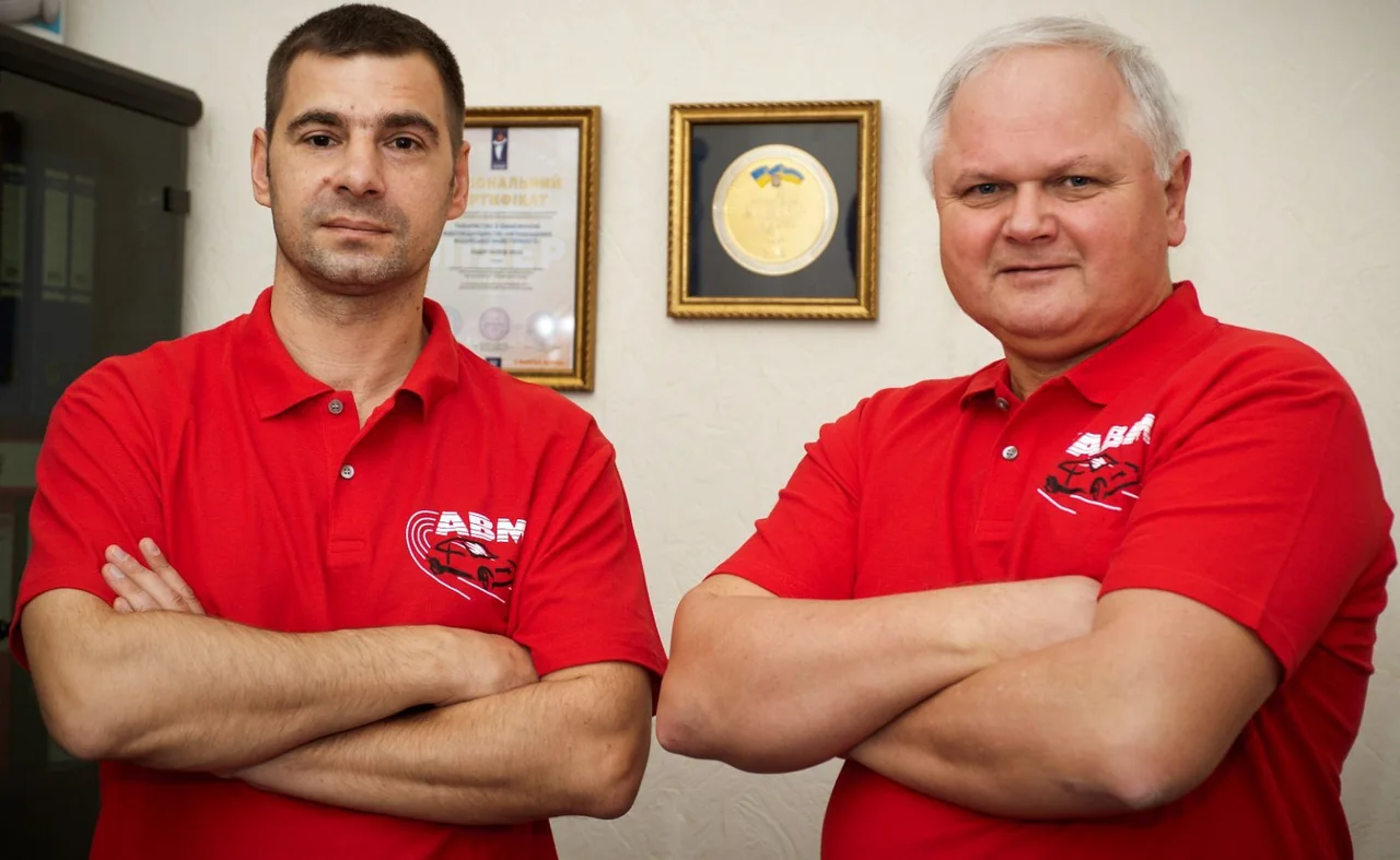 Двоє представників АВМ у червоних фірмових поло в офісі академії
